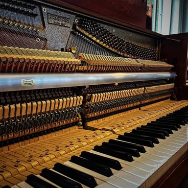 A technician adjusting the strings of a piano during tuning.
