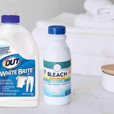 A bottle of laundry bleach beside white clothing.