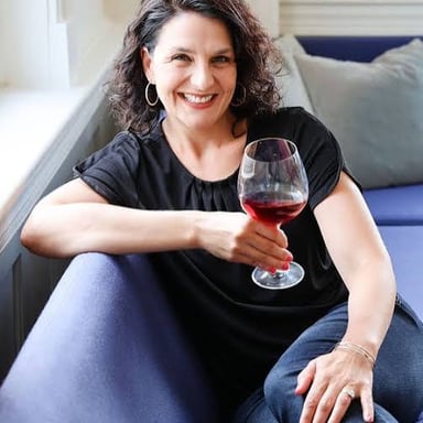 A wine expert discusses a bottle with people at a tasting.