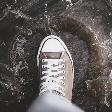 A shoe splashes through a shallow puddle.