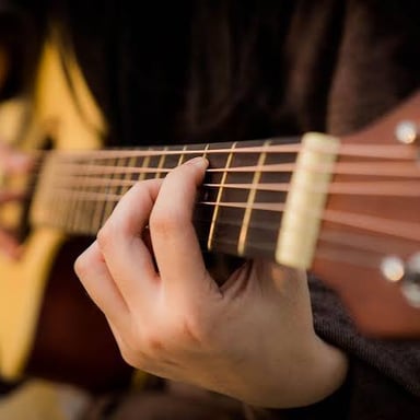 A person strumming the strings of an acoustic guitar.