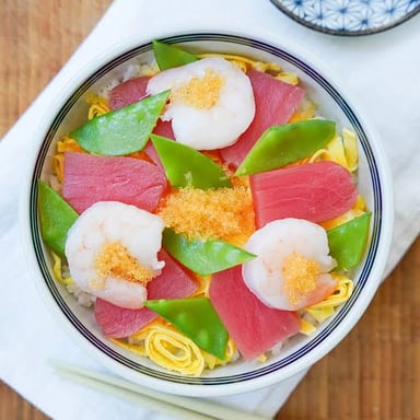 A bowl of chirashi sushi with fish roe among the toppings over rice.