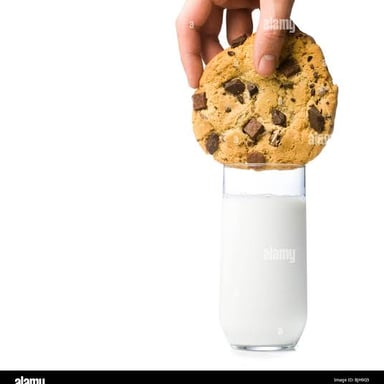 A cookie being dipped into a glass of milk