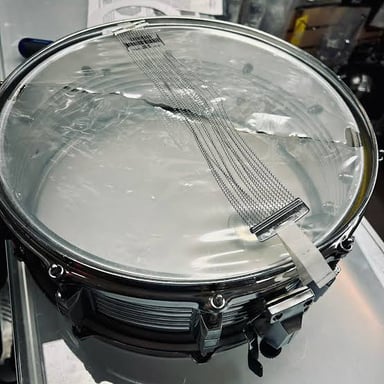 A snare drum with its wires visible beneath the drumhead.