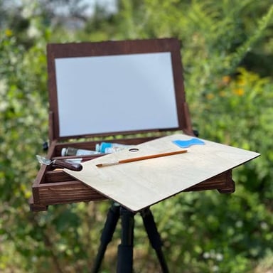 An artist’s easel with three legs supports a canvas upright.