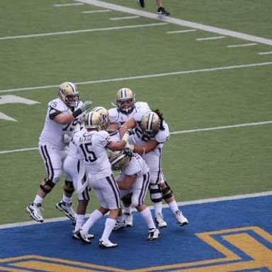 A football player celebrating after scoring a touchdown in the end zone.