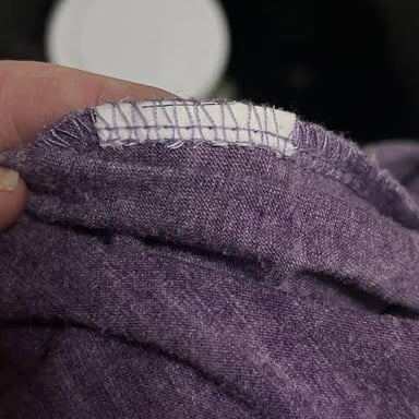 A fabric clothing label sewn inside a garment, showing care instructions.