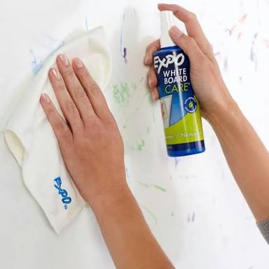 A hand wiping marks from a small slate board.