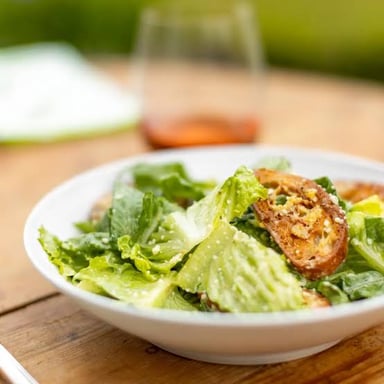 A Caesar salad topped with croutons and shaved Parmesan