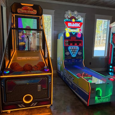 A game arcade with colorful claw machines beside video game cabinets.