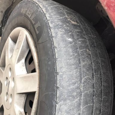 A car tire with tread worn nearly smooth.