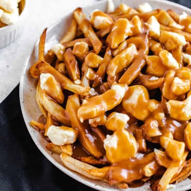 A serving of poutine topped with cheese curds and gravy.