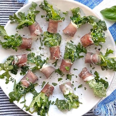 Peppery arugula leaves served alongside thin slices of prosciutto.