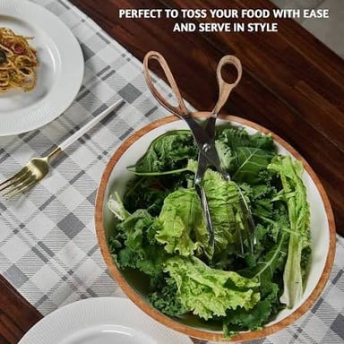 A pair of serving tongs gripping lettuce leaves.