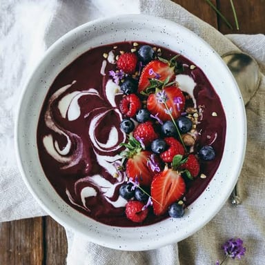 Dark-purple açaí berries beside a bowl of blended açaí.