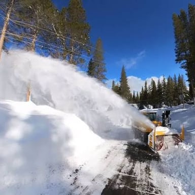 A vehicle-mounted plow pushing snow off a road.