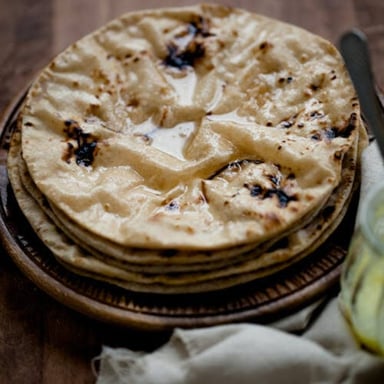 A plate of roti beside wheat flour used to make it.