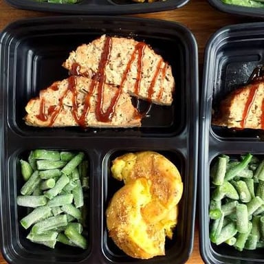 A prepared meal arranged in separate sections of a tray, ready to be heated.