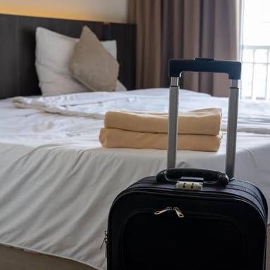 A hotel guest room with a suitcase, suggesting an overnight stay.