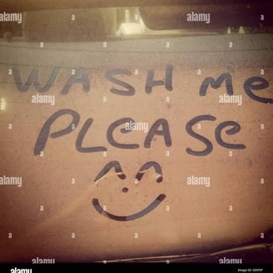 A dusty car with “Wash Me” written across its surface.