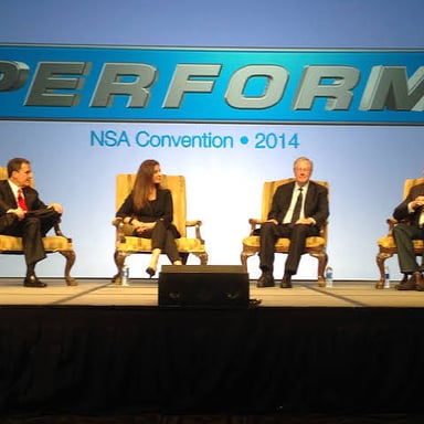 Several presenters seated together onstage for a moderated conference discussion.