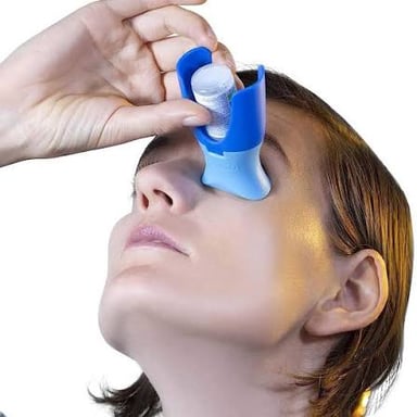 A bottle of eye drops being used to place a drop in an eye.
