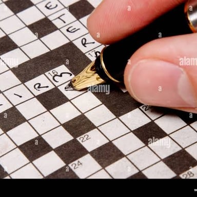 A hand writing answers into a crossword grid with a pen.