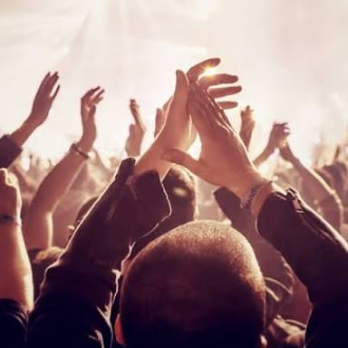 Audience members clapping in applause at a performance.