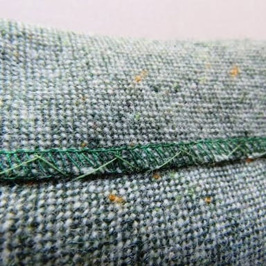 A close view of fabric folded and sewn along a garment edge.
