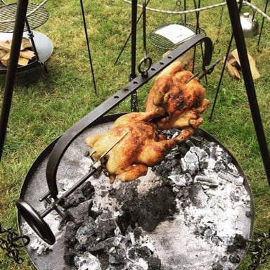 A cooking spit holding food as it turns over a heat source.