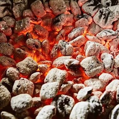Charcoal briquettes glowing in a barbecue grill.