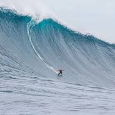 A surfer rides a breaking ocean wave.