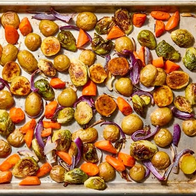 Vegetables browning as they roast on a tray in an oven.