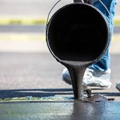 Dark, sticky paving material being applied to a road.