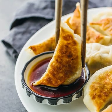 Chinese jiaozi dumplings with folded dough wrappers, served with dipping sauce.