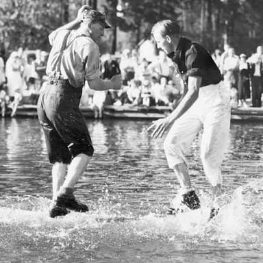 Two competitors balance on a floating log during a log-rolling contest.