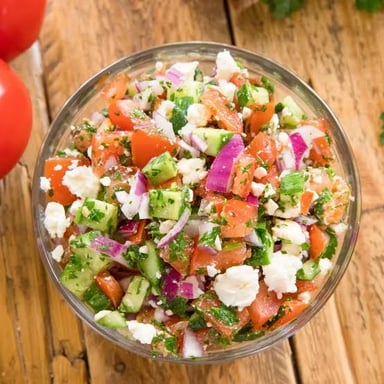 A Greek salad topped with crumbled feta cheese.