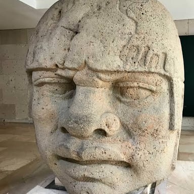 A monumental carved Olmec stone head, a distinctive work of ancient Mesoamerican art.