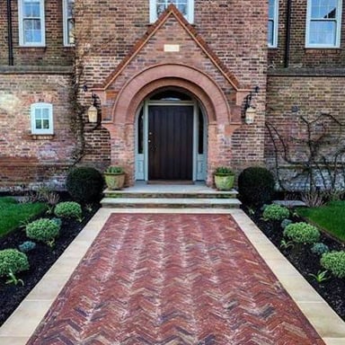 Rectangular brick pavers laid in a pattern to form a driveway.
