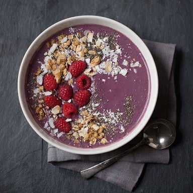 Dark purple açaí berries beside an açaí smoothie bowl.