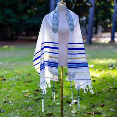 A Jewish prayer shawl draped over the shoulders, with fringes visible at its corners.