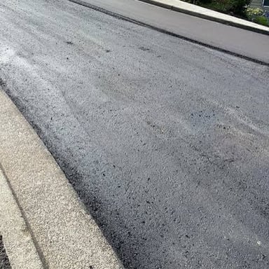 A dark, glossy layer of tar spread across a road surface.