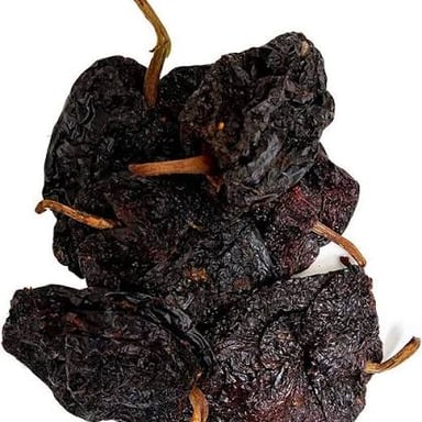 Dark green fresh poblano peppers beside dried ancho chiles.