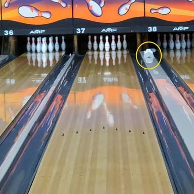 A bowling lane leads toward a full set of pins.