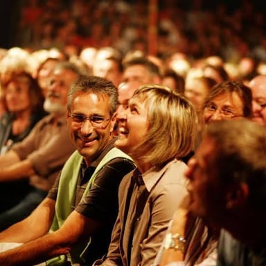 A comedian performing stand-up comedy for a laughing audience.