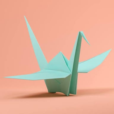 Hands folding paper into an origami crane.