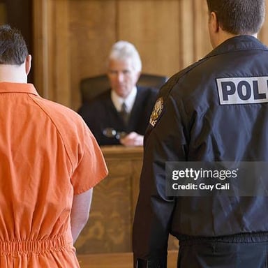 A courtroom scene with a defendant facing a judge during a trial.