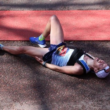 A tired runner rubbing sore leg muscles after a race.