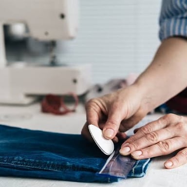 A tailor pinning or sewing a clothing alteration.