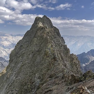 A steep, rugged rock face projecting from a mountain hillside.
